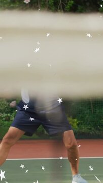 Vertical video: Senior man practicing returning ball, lunging twohanded on tennis court with stars
