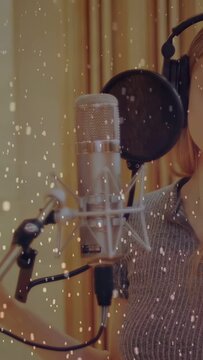 Vertical video: Female singer putting on phones, leaning into mic, singing music with snow overlay