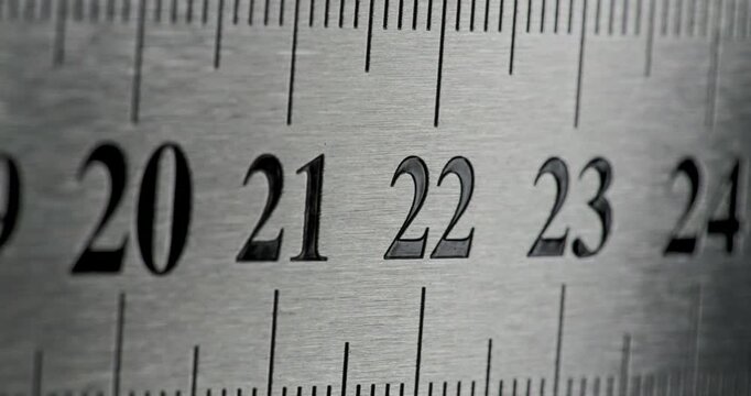 Slow Pan Over Metal Ruler. Smooth slow movement across extreme close-up of metallic ruler with black numbers and brushed surface.