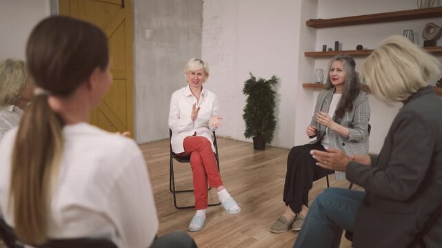 Joyful blonde woman applauding in business or art meeting, vertical portrait of smiling mature lady. Women community or group therapy for mental health, business coach and teambuilding in company