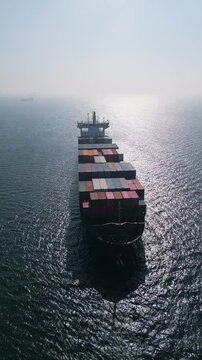 Aerial view of a large container ship in the open sea at sunset