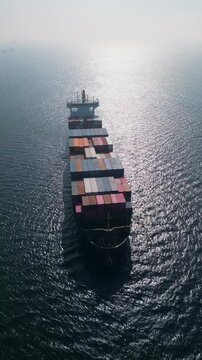 Aerial view of a large container ship in the open sea at sunset