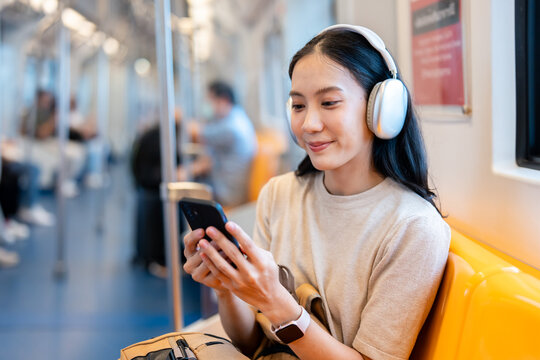 Asian young woman sitting on subway train seat while traveling in city. 