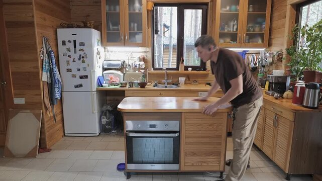 Man cleaning wooden table surface in cozy home kitchen, wiping countertop with cloth during routine household maintenance
