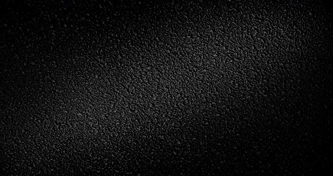 Abstract black texture. The slow, smooth diagonal movement of a dark, rough surface moving in a soft beam of light.