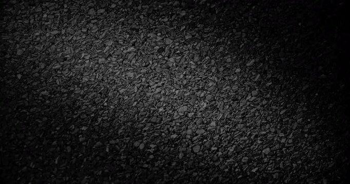 Black Gravel Texture. Slow Diagonal Panning. Extreme close-up of rough black granular surface with dramatic low key lighting.