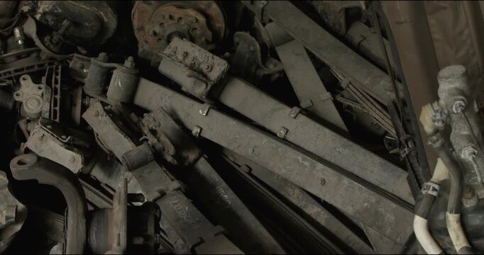 Dusty automotive spare parts in old repair workshop with metal rims and machinery components. Industrial garage storage scene featuring used mechanical equipment, vintage engineering salvage backgroun