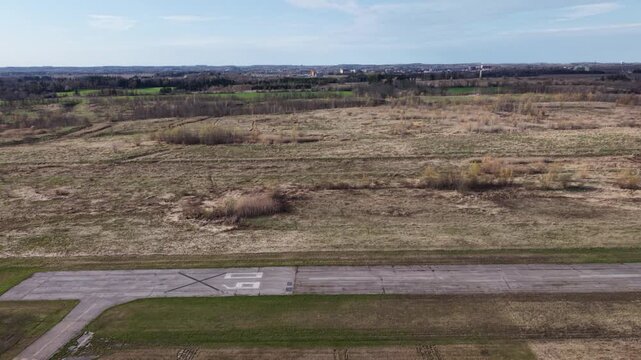 Aerial shot flying rightward along the length of the decommissioned runway 09 at Markham Airport, showing cracked asphalt and vast open fields