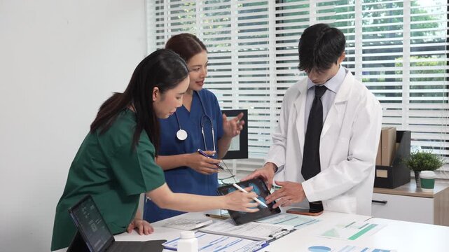 Medical team meeting at desk reviewing digital tablet with brain scan images, charts and documents; doctors and nurses in scrubs and lab coat discussing patient data, modern healthcare collaboration