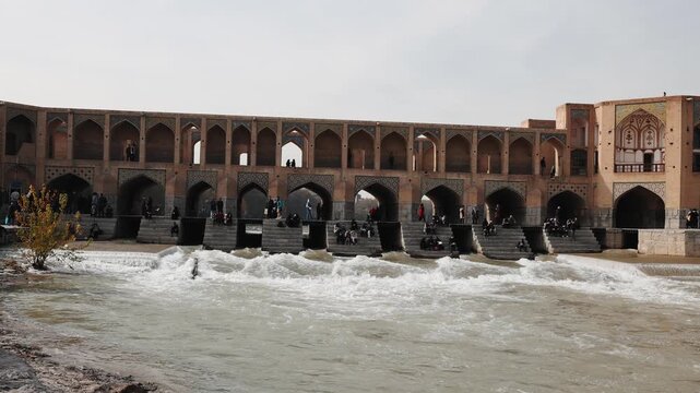 Khaju Bridge in Isfahan, Iran, reflected in the calm waters of the Zayandeh River. Scenic view of the historic 17th century Persian bridge with traditional arches and stone architecture