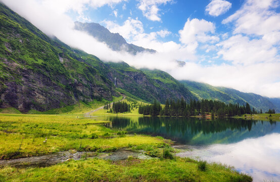 Beautiful summer lake landscape with mountain in the Autria Alps. Wonderful hiking spot. Alpine lake with high mountains. Pine trees. Hohe Tauern near Zell am See / Kaprun