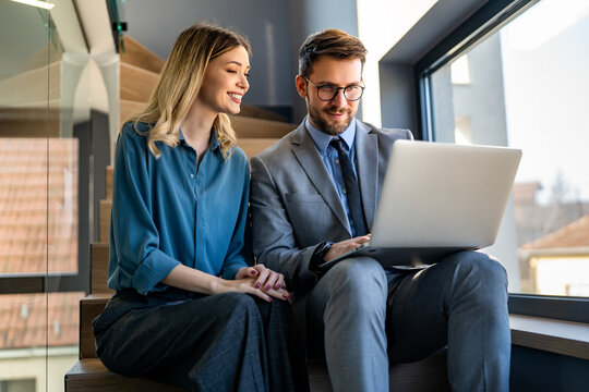 Happy multiethnic businesspeople laughing while collaborating on a new project in an office.