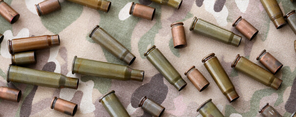 Obraz premium Big amount of shells cartridges from assault rifle bullets on old camouflage fabric
