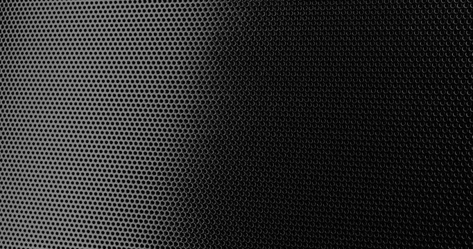 Black Perforated Metal Mesh. Smooth slow movement across extreme close-up of dark perforated metal grid with dramatic side lighting.