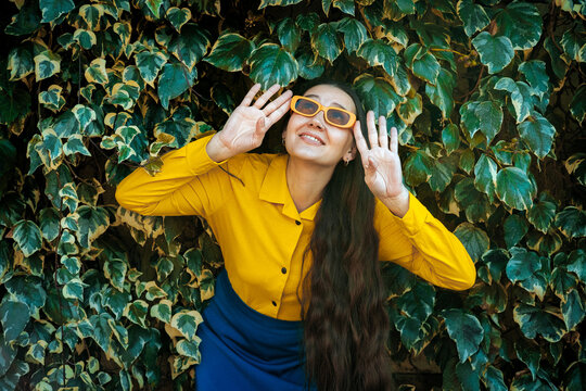 Smiling model looking up in yellow shirt against outdoor ivy wall