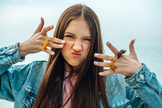 Portrait of girl showing a mustache ring and a funny face outdoors