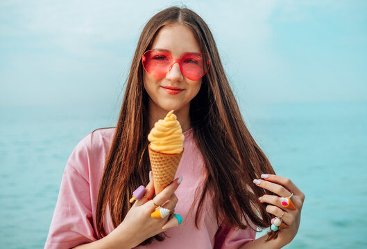 Girl holding ice cream cone by the sea during summer