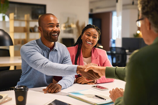 Businessman shaking hands with couple after deal