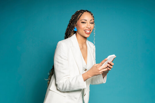 Smiling businessperson in white blazer holding smartphone