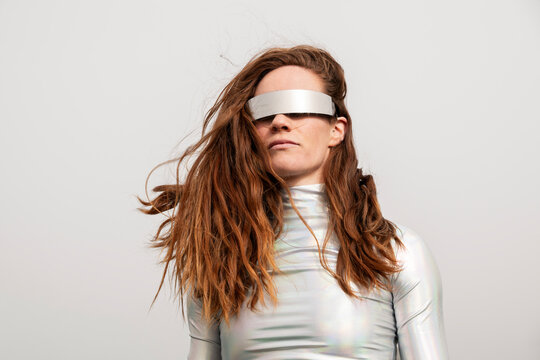 Model with red hair in metallic clothing and visor outdoors