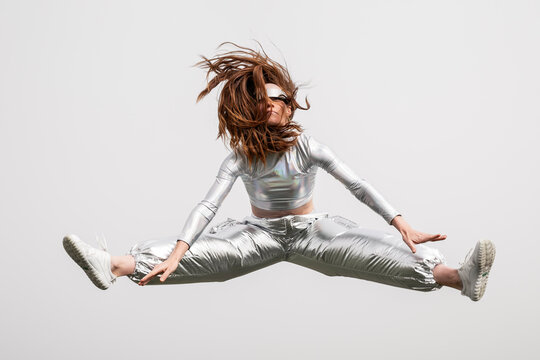Futuristic model jumping midair in metallic clothing and VR headset
