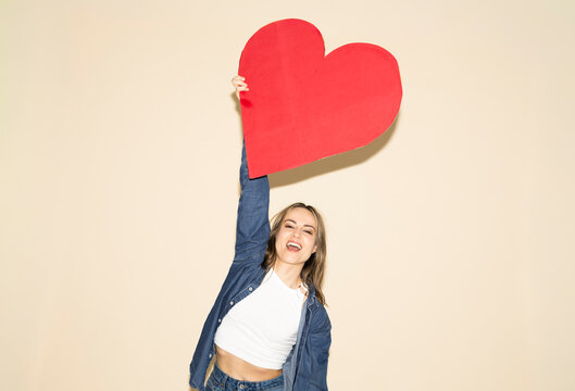 Woman holding up a large red paper heart to show love and empathy