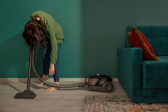 Exhausted from doing housework leaning on a vacuum cleaner at home