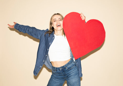 Woman holding a large red paper heart expressing joy and brand loyalty