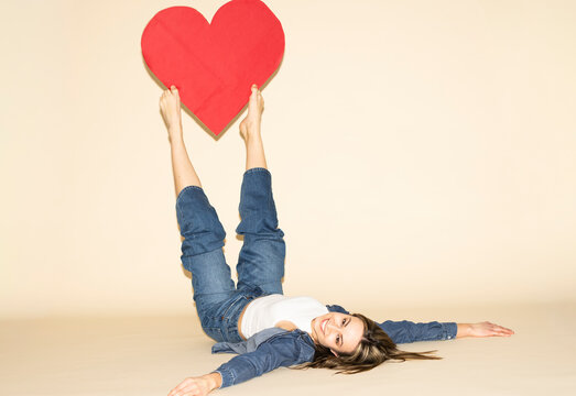 Smiling model holding a red paper heart with bare feet