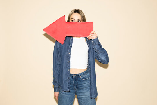 Model holding red paper arrow over face for direction and strategy