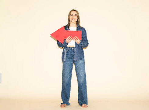 Smiling woman holding a red paper arrow indicating direction