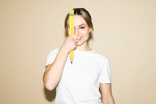 Smiling designer holding large pencil for creativity concept