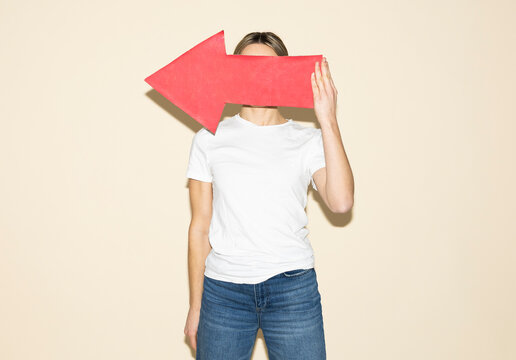 Woman holding a red paper arrow indoors to show direction and strategy