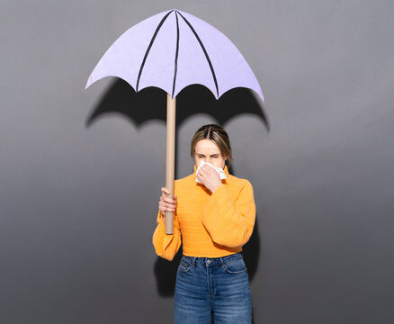 Patient with cold blowing nose under paper umbrella indoors