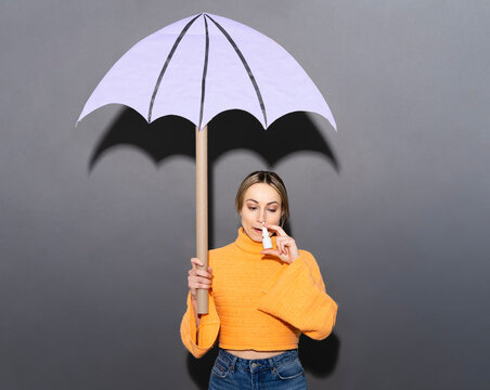 Patient using nasal spray under a purple paper umbrella
