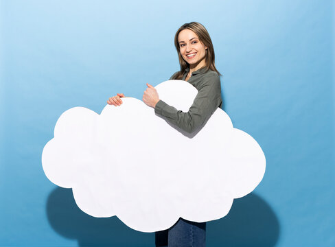 Woman smiling holding a blank white paper cloud on blue background