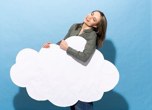 Woman holding a paper cloud and smiling on a blue background