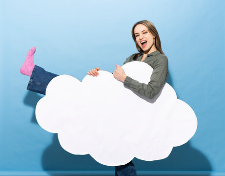 Woman holding a blank paper cloud with copy space on a blue background