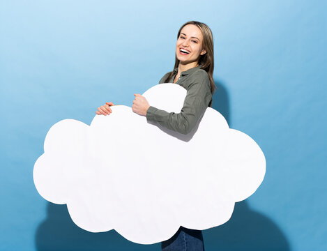Smiling model holding a blank paper cloud on blue background