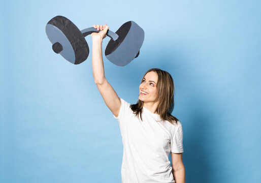 Smiling fitness enthusiast lifting paper dumbbell indoors