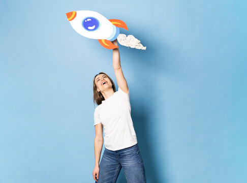 Smiling entrepreneur holds a handmade paper rocket