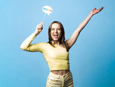 Woman celebrating with hooray speech bubble on blue background
