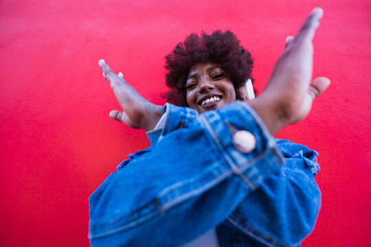 Smiling model with headphone crossing arms on red background