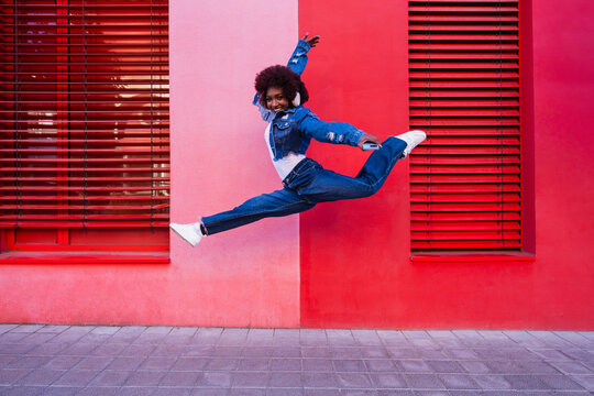 Urban dancer jumping outdoors listening to music