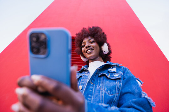 Smiling with a smartphone and headphones outdoors