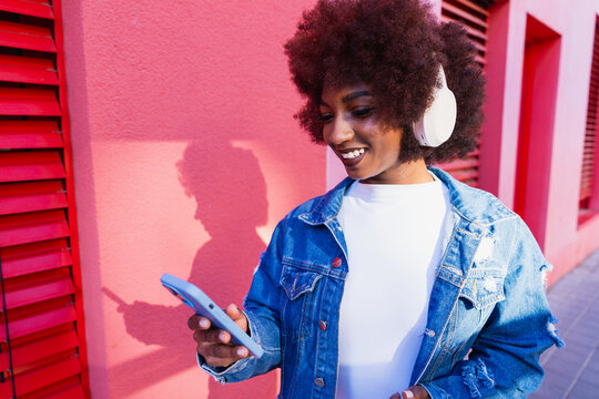 Smiling music lover using smartphone with headphone outdoors