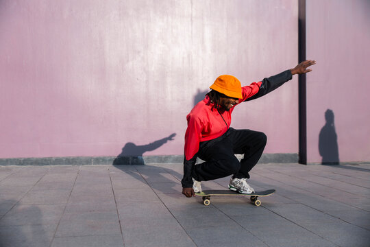 Skateboarder crouching on skateboard by purple wall in Barcelona