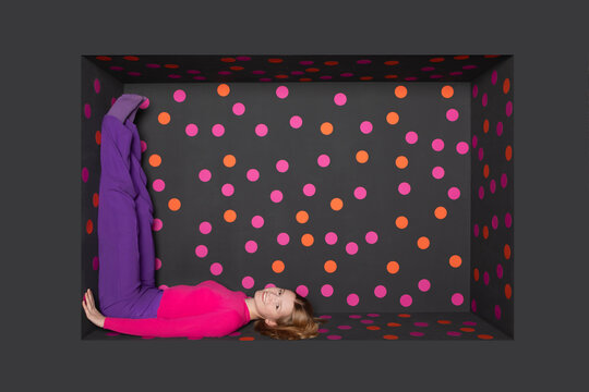 Smiling teenager lying in alcove over black background with colored dots