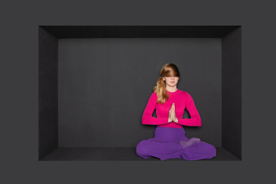 Blond teenage girl practicing prayer pose yoga over black background