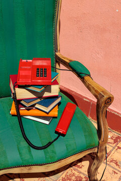 Vintage red telephone on stacked books on a green armchair
